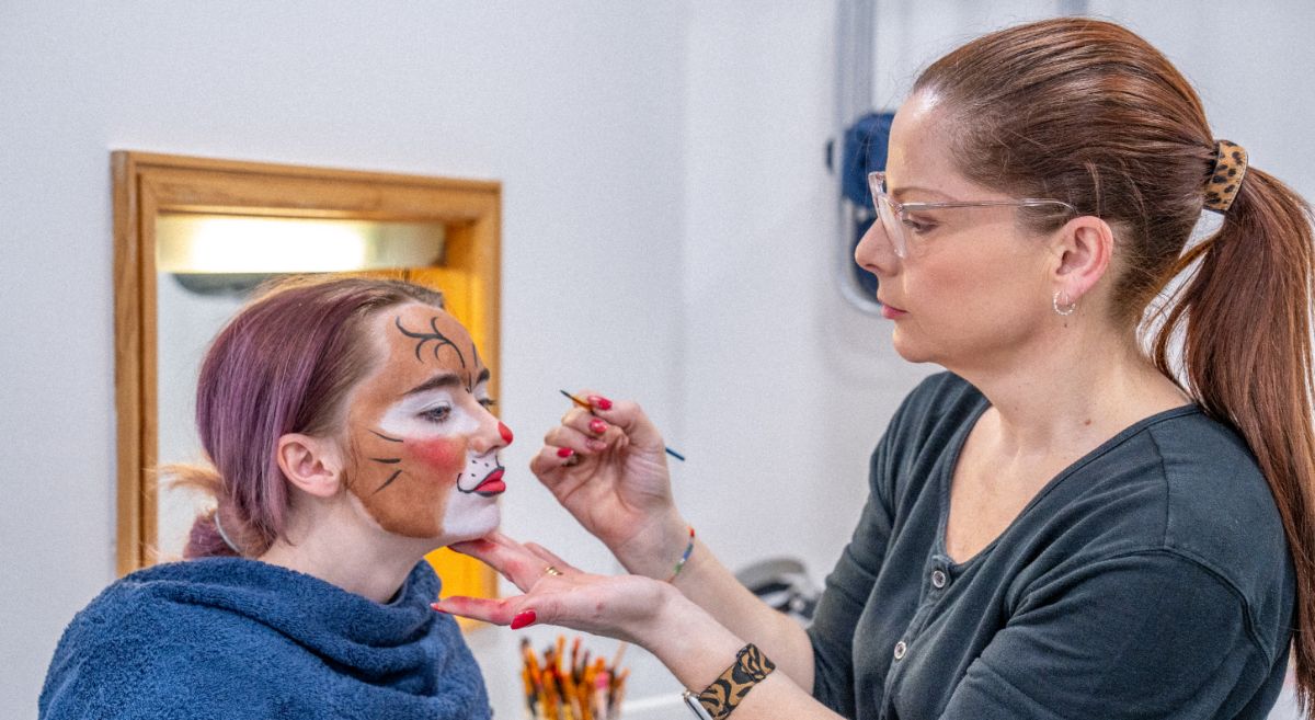 Makeup artist applying face paint to model.